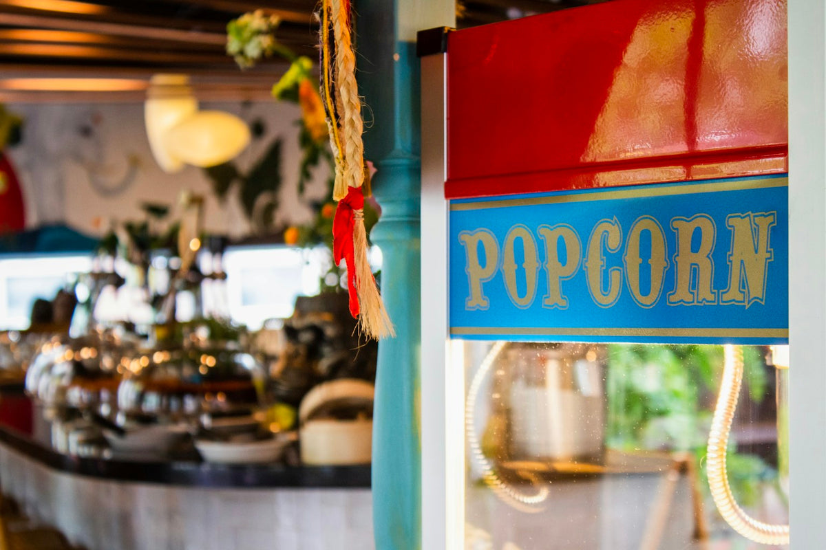 A red and blue popcorn machine popping fresh popcorn