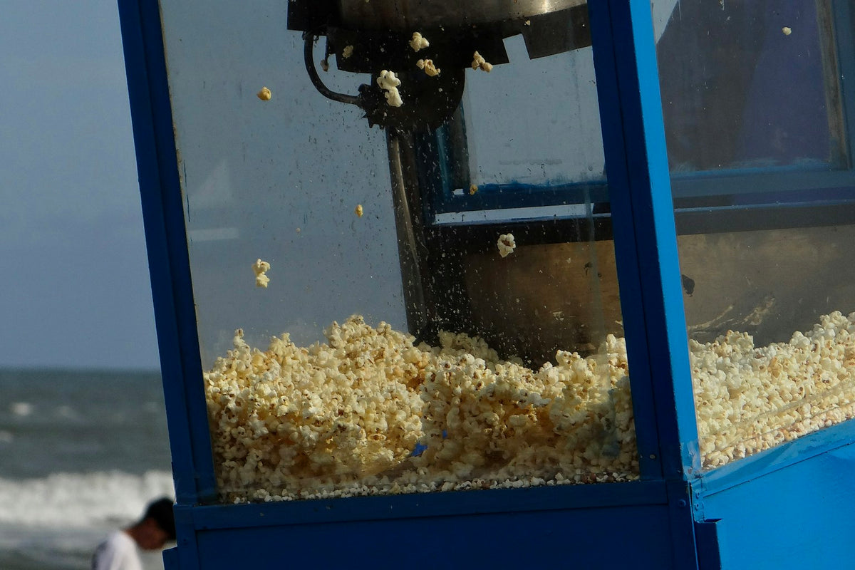 A commercial popcorn machine popping a batch of fresh popcorn